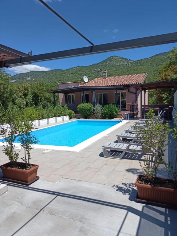 a swimming pool in a yard with chairs and a house at Villa Meja in Hreljin