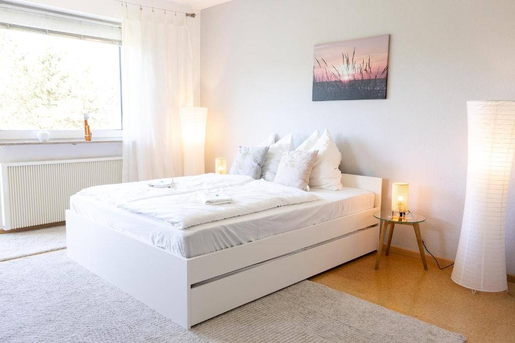 a white bed in a white bedroom with a window at Strandnahe Ferienwohnung mit Privatweg, Spielplatz & Aufzug in Sankt Peter-Ording