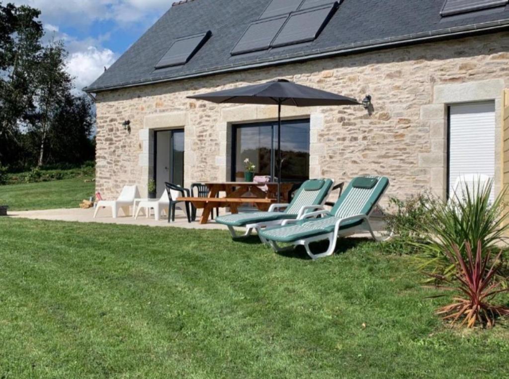 a patio with chairs and an umbrella and a table at Domaine de Kerroux in Bannalec