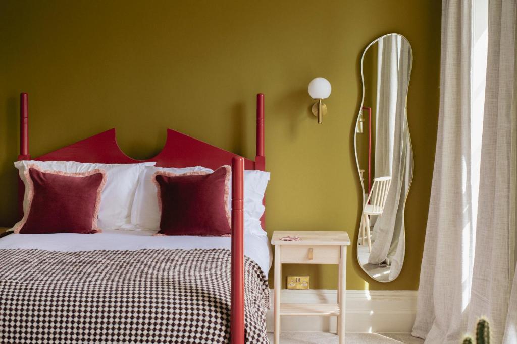 a bedroom with a bed with a red headboard and a mirror at Merchant's House in Derry Londonderry
