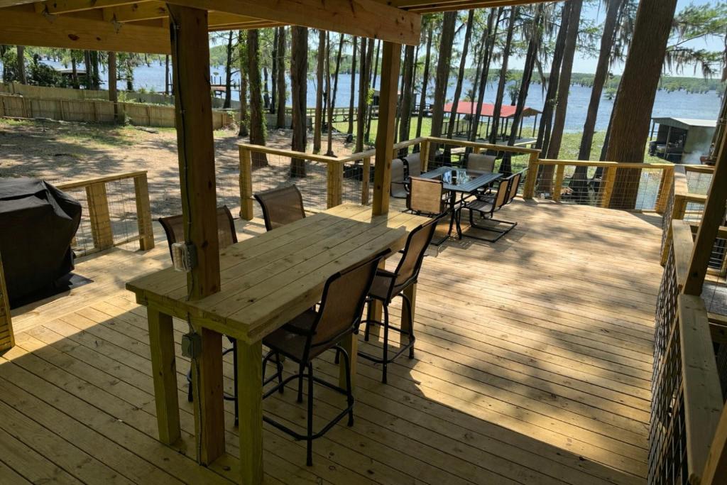 a wooden deck with a wooden table and chairs at Canvasback Cove on Caddo Lake in Jefferson