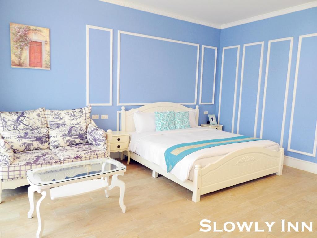 恆春的住宿－墾丁慢遊民宿，卧室拥有蓝色的墙壁,配有一张床和一张沙发