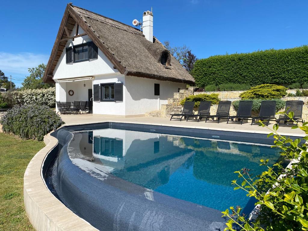 a house with a swimming pool in front of a house at Perla Balaton in Csopak