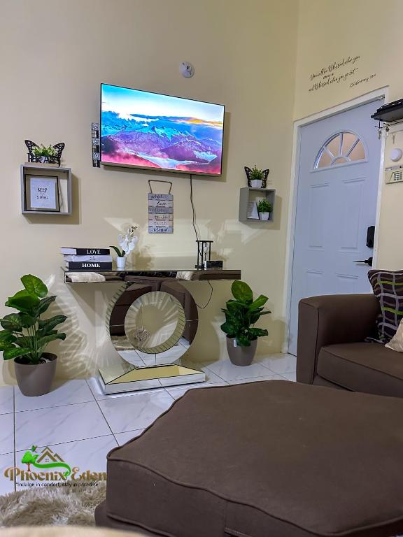 a living room with a couch and a tv on the wall at Phoenix Eden in Portmore