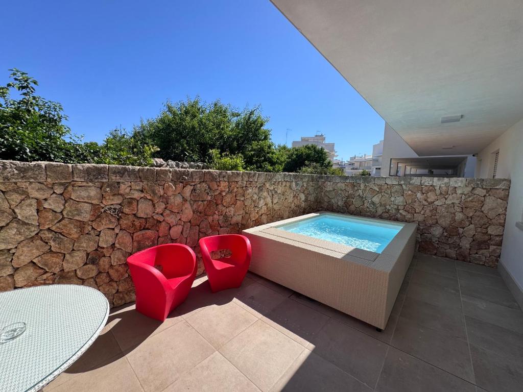 a swimming pool with two red chairs and a table at Venti D'Amare Suites in Polignano a Mare