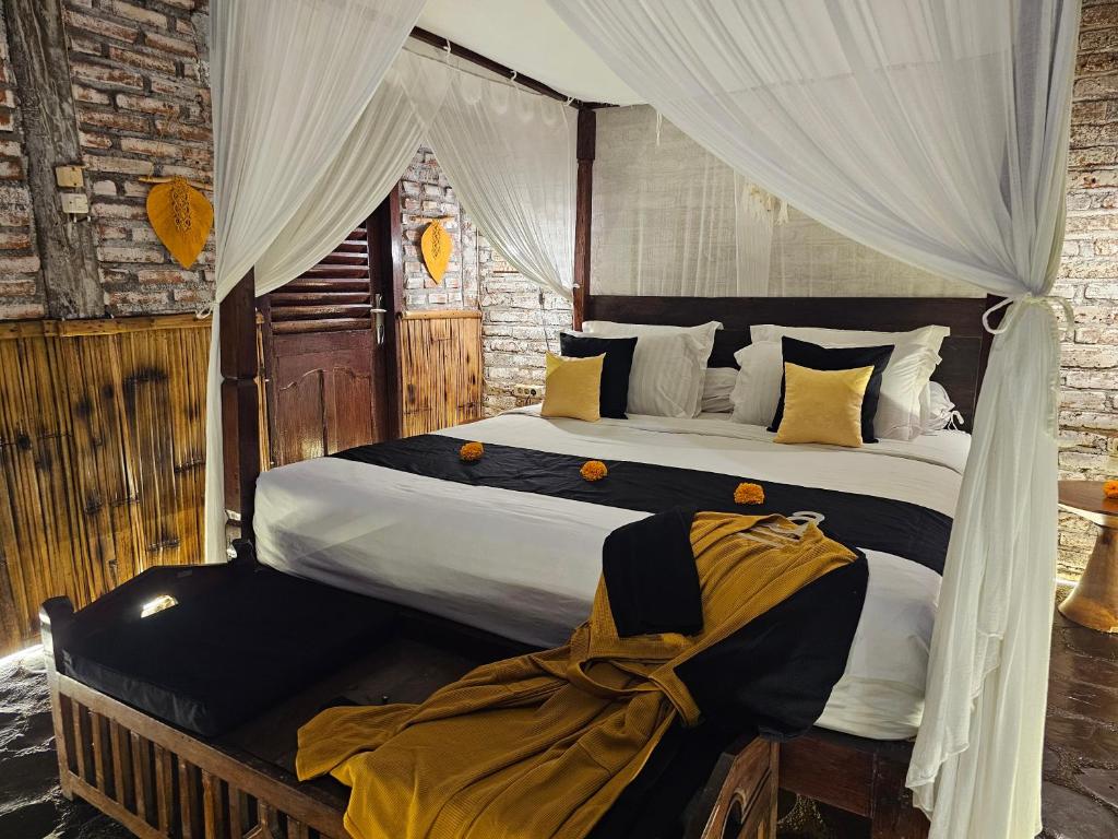 a bedroom with a large bed with white curtains at Santhiku Hotel & SPA in Lovina