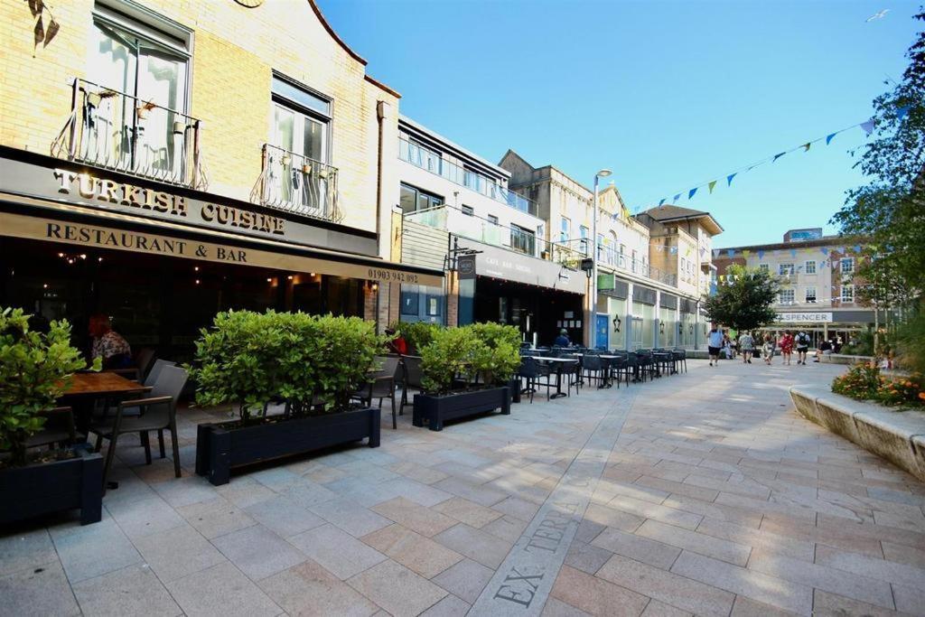 an empty street with tables and chairs and buildings at Wonderful Worthing Beach Walk Flat in Worthing