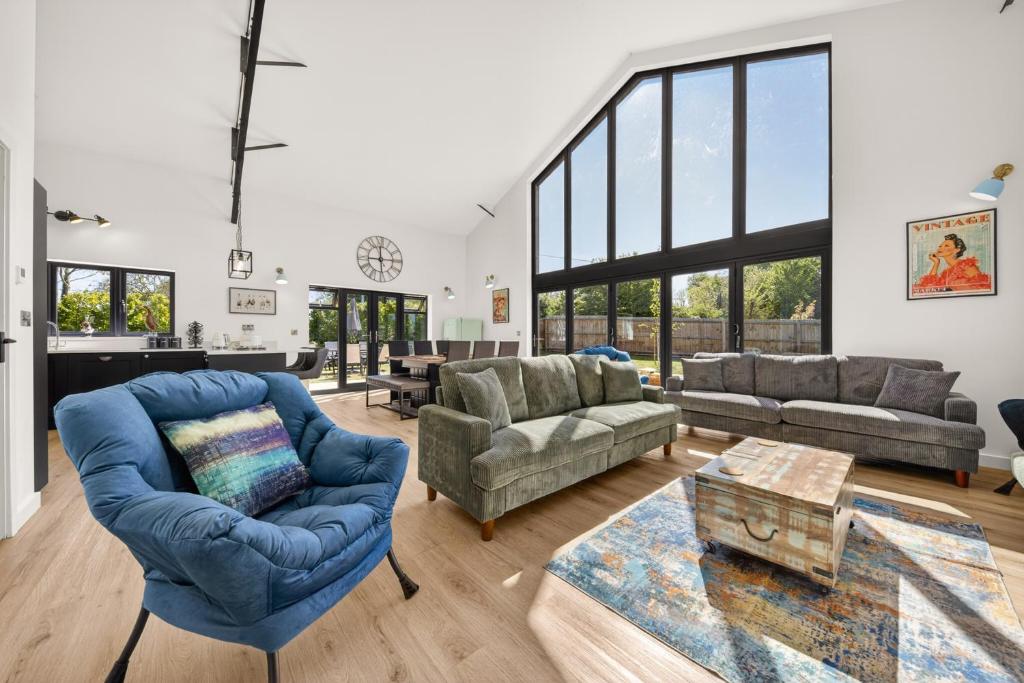 a large living room with blue chairs and a couch at Luxury Norfolk Barn for 12 with Hot Tub , Games Room & EV Car Port in Lenwade