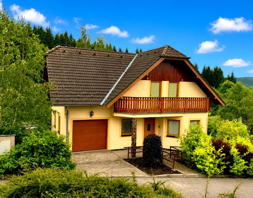 a house with a balcony and a garage at Villa Slupečná in Lipno nad Vltavou