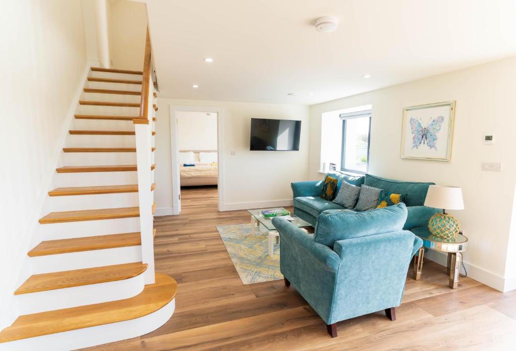 a living room with a staircase and a blue couch at The Summit - Skellig Coast in Cahersiveen