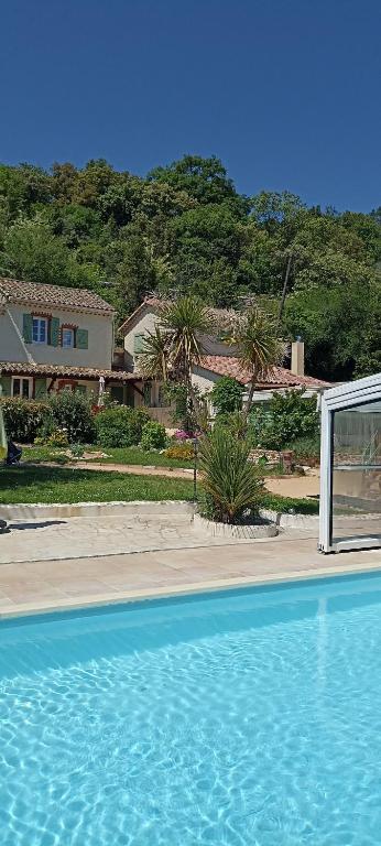 a blue swimming pool with a house in the background at Gîte La Pequelette in Saint-Ambroix