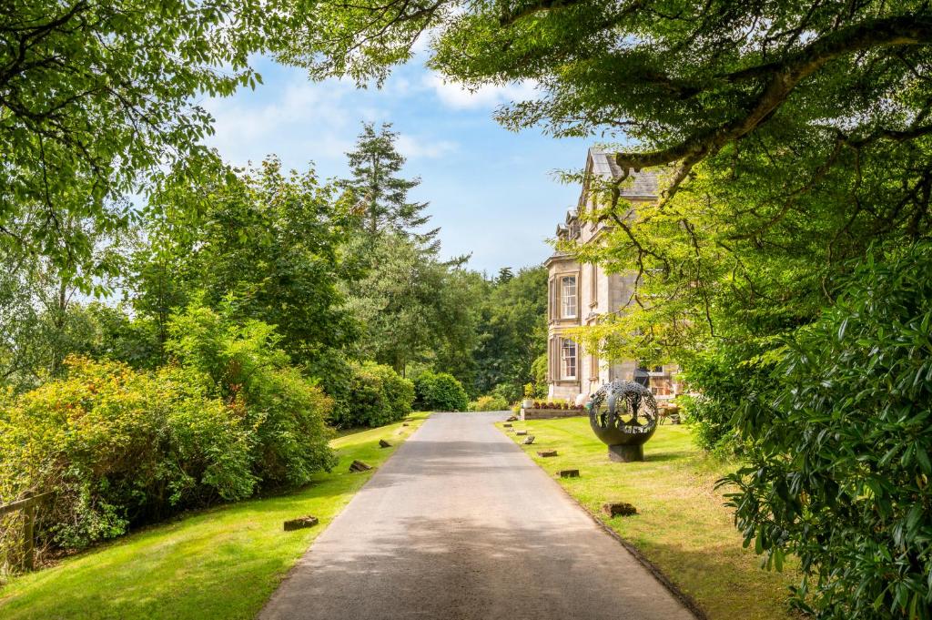 a road in front of a house with trees at Garden Flat- Private Luxury in Ashkirk