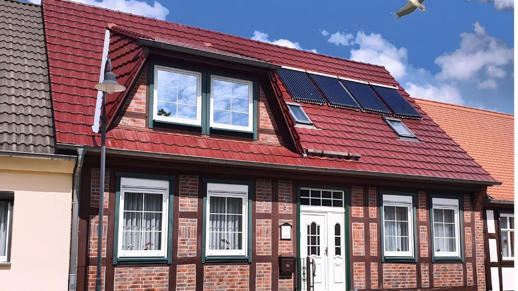 a red roofed house with solar panels on it at Ferienwohnung 1 in Bad Wilsnack