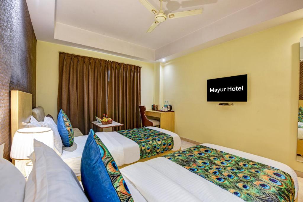 a hotel room with two beds and a flat screen tv at Hotel Mayur in New Delhi