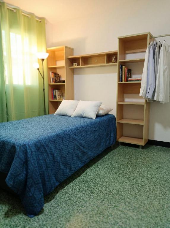 a bedroom with a bed with a blue comforter and shelves at La Milagrosa in Caracas