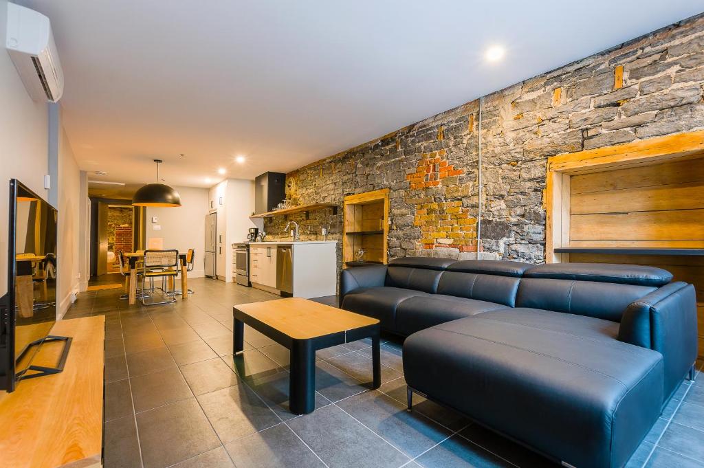 a living room with a couch and a stone wall at Les Lofts St-Paul - Par Les Lofts Vieux-Québec in Quebec City