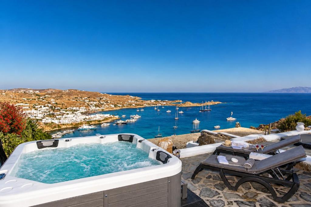 a hot tub on a patio with a view of the ocean at Mykonos Psarou Place with Private Jacuzzi in Psarou