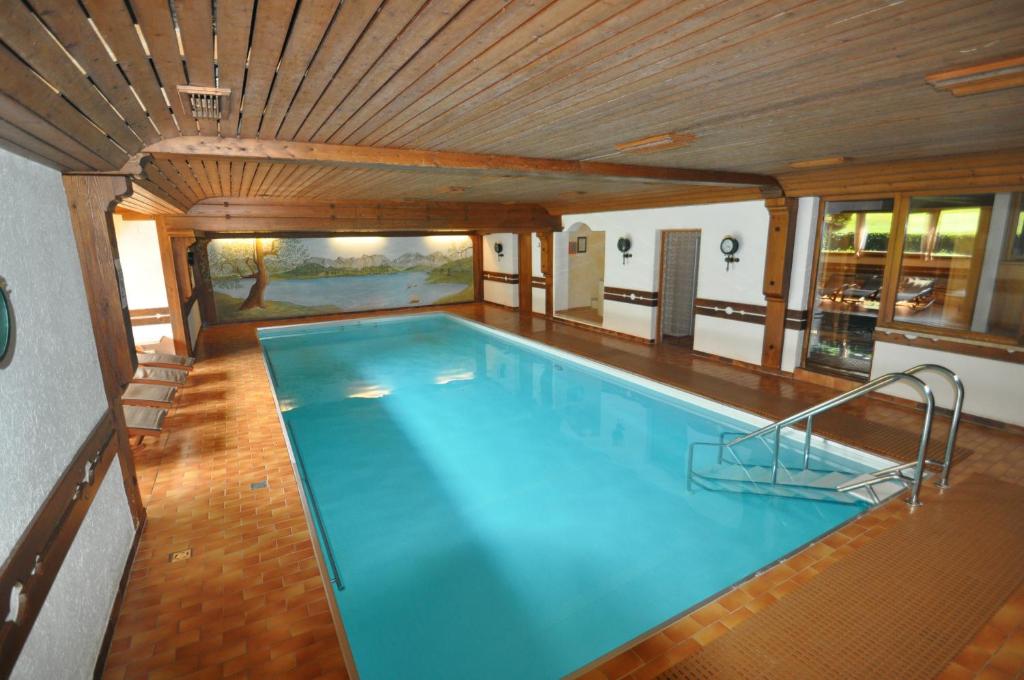 a large swimming pool with a wooden ceiling at Appartementhaus Alpenrose in Wallgau