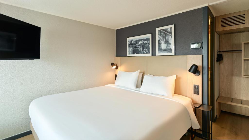 a large white bed in a hotel room at Campanile NATURE - Meaux in Meaux