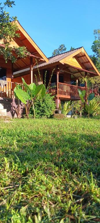 a house with a deck and a grass yard at Tetebatu Sunrise Homestay in Tetebatu