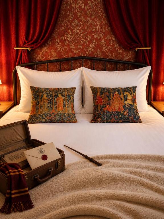 a bed with two pillows and a suitcase on it at La Maison de Traverse in Vichy