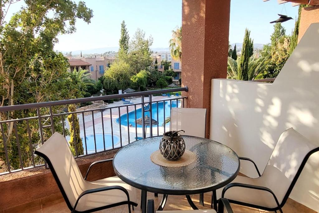 a table and chairs on a balcony with a pool at Mandria Gardens Paradise II in Mandria