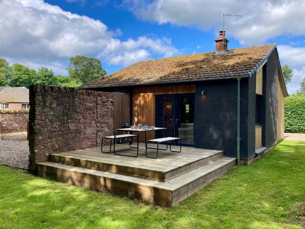 a house with a wooden deck with a table and chairs at Hygge House in Woodside
