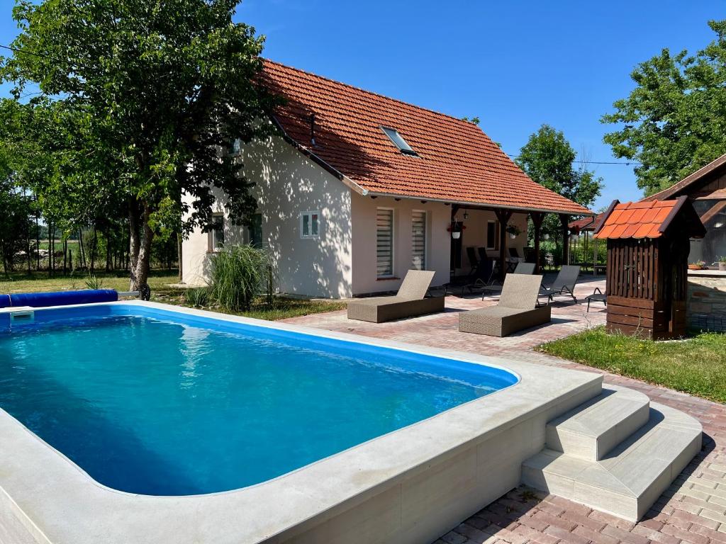 a swimming pool in front of a house at Akácos Tanya Szarvas in Szarvas