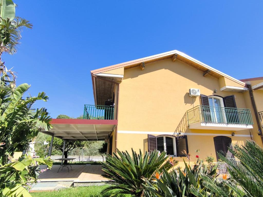 a yellow house with a balcony and plants at GuestHost - Eden Green Oasis in Giardini Naxos
