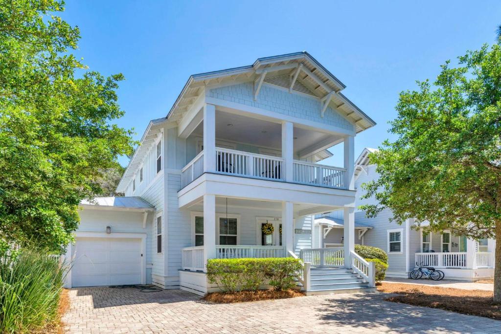 a white house with a balcony and trees at Beachful Bliss in Santa Rosa Beach