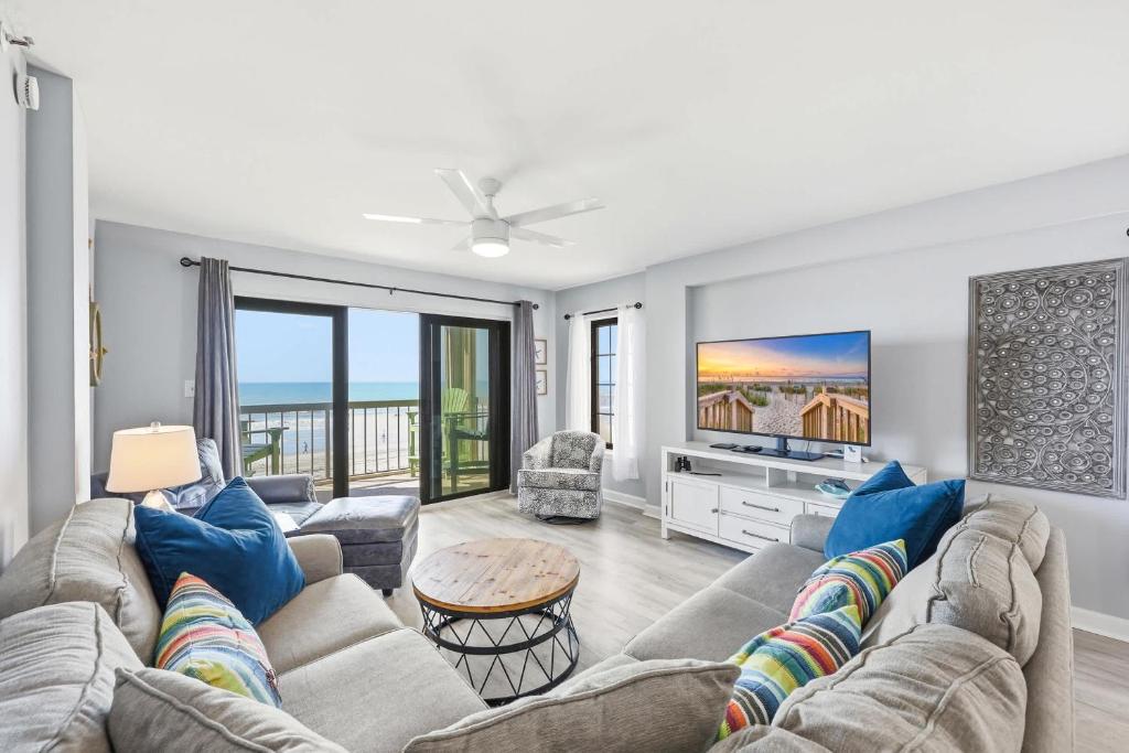 a living room with a couch and a tv at Sandy Bits Oceanfront Premium Condo with Pool in Myrtle Beach