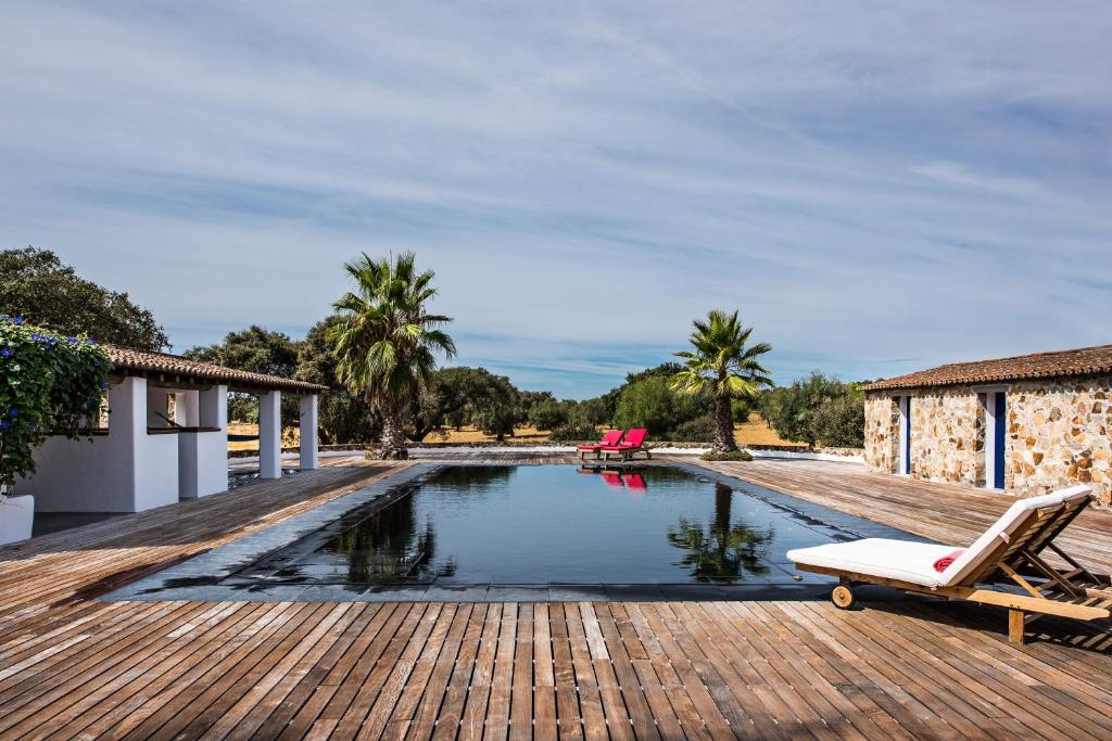 a swimming pool with a lounge chair on a wooden deck at Herdade dos Alfanges "THE BARN" in Viana do Alentejo