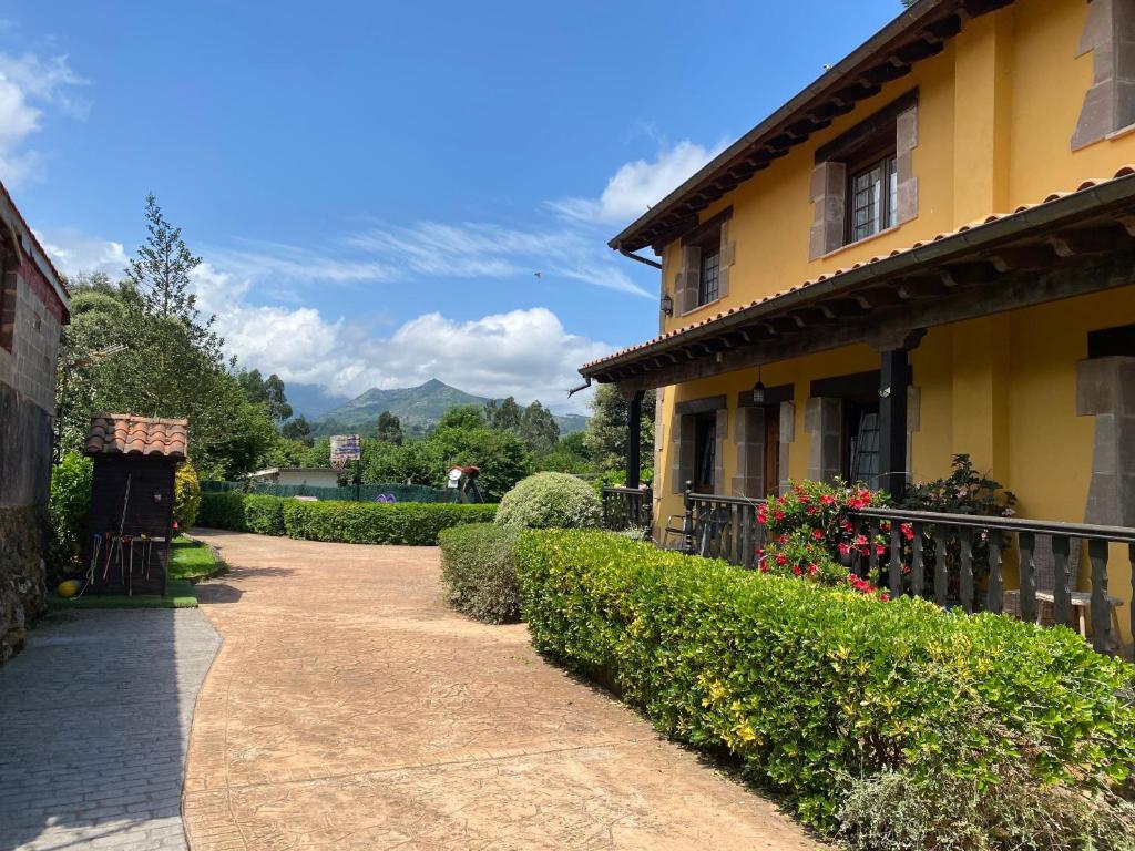 a walkway next to a yellow house with bushes at Los Avellanos Casa 1 in Celis