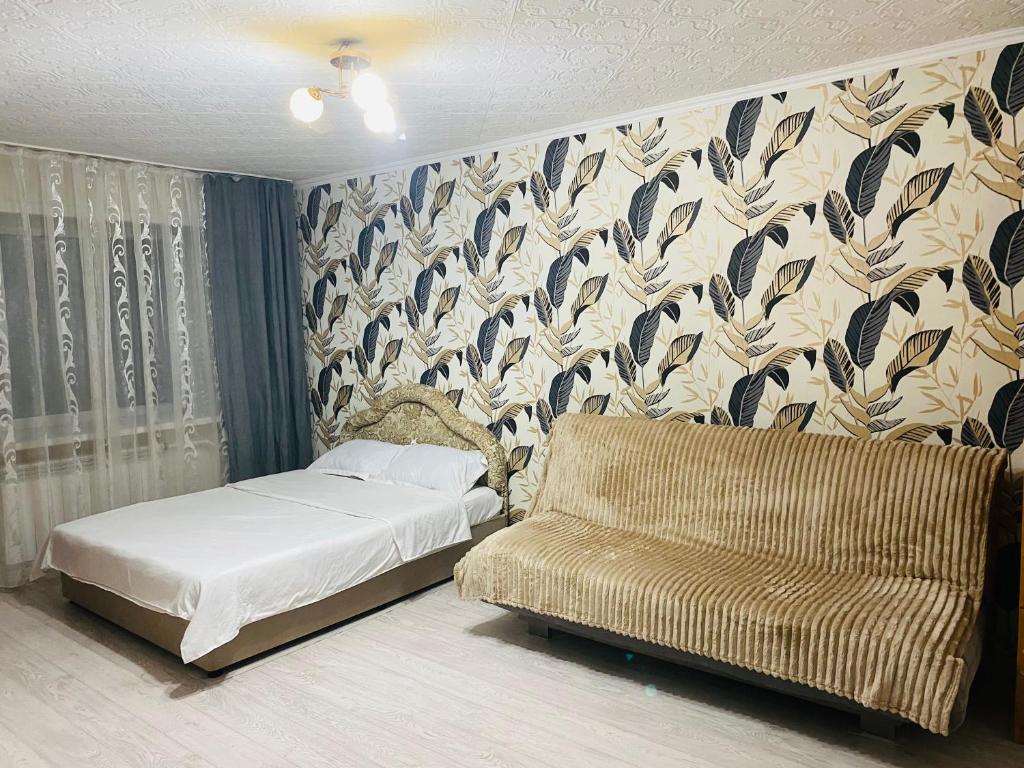 a bed and a couch in a room with a wallpaper at Comfort Home Gogolya in Karagandy