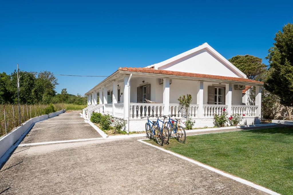 a white house with bikes parked in the driveway at Serenity Apartments, Next to the Beach in Agios Georgios