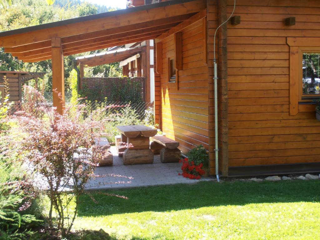 a wooden cabin with a bench in the yard at Chata pod Lazíkom in Liptovský Hrádok