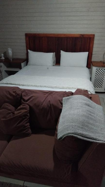 a large bed with a wooden headboard and white sheets at 1atKruger Unit 2 in Mokopane