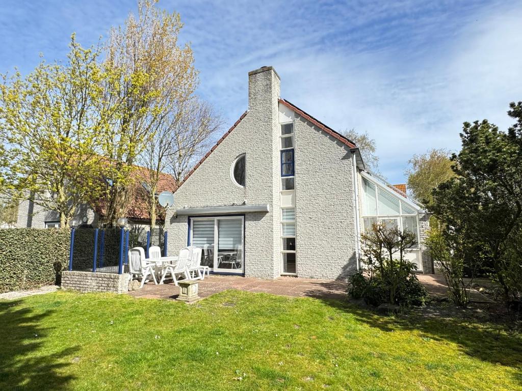 a house with two white chairs in the yard at Ooghduyne 89 in Julianadorp