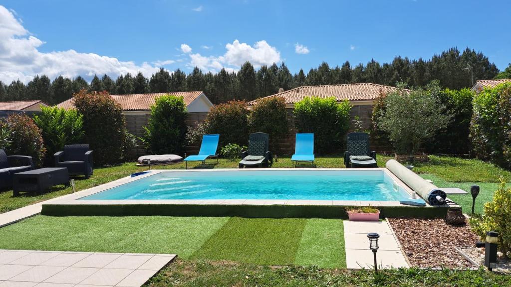 a swimming pool in a yard with blue chairs at TURQUOISE in Linxe