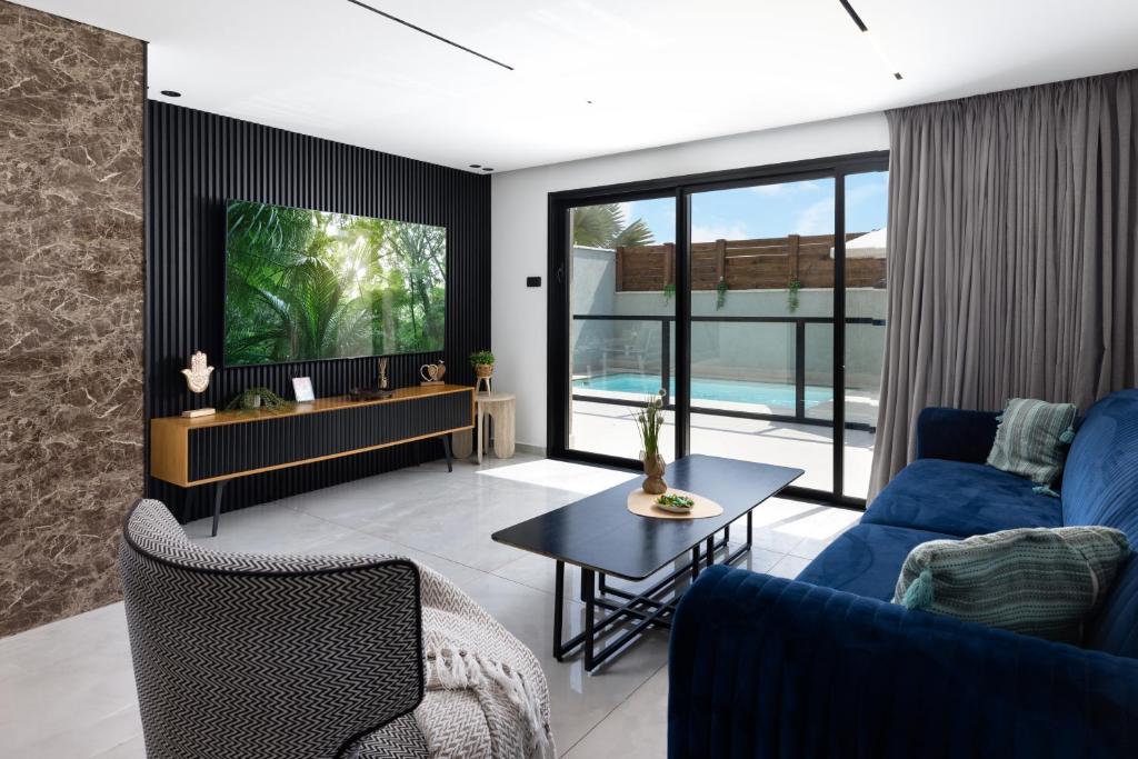 a living room with a blue couch and a tv at Coral suites Boutique in Eilat