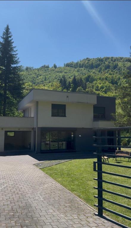a large white building with a hill in the background at Villa Bukvic in Zavidovići