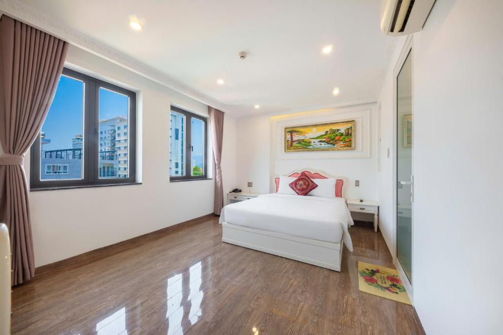 a bedroom with a white bed and large windows at Michael Hotel in Nha Trang