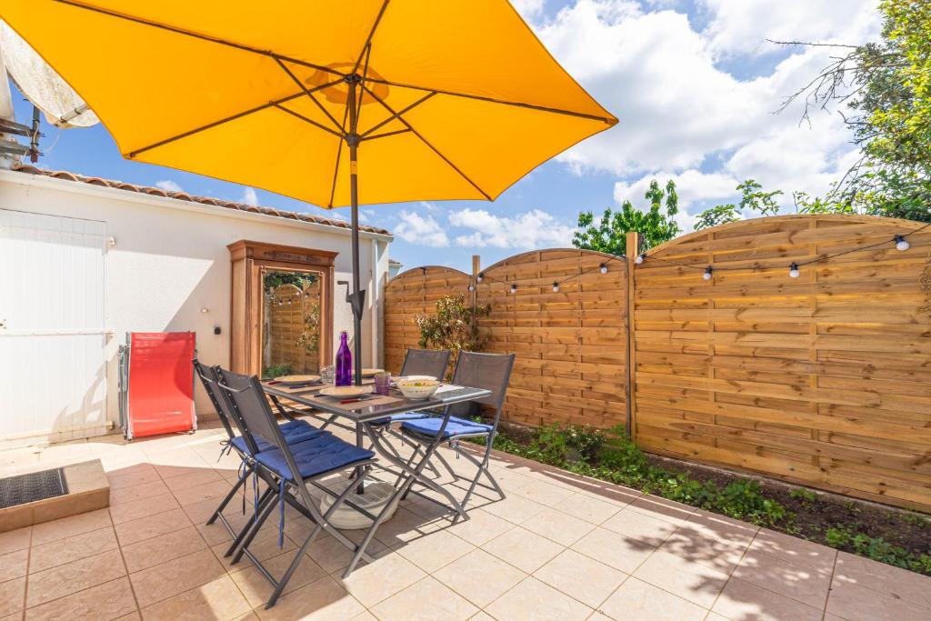 a patio with a table and a yellow umbrella at Location Oléron centre La Cotinière in Saint-Pierre-dʼOléron