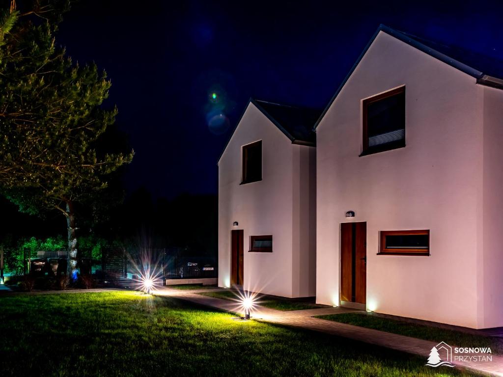 a white house with lights on the grass at night at Domki Sosnowa Przystań w Rozewiu Jastrzębia Góra - Jacuzzi Forest in Jastrzębia Góra