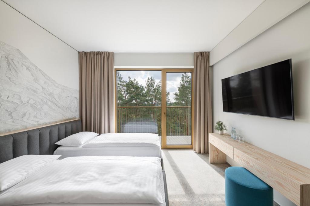 a hotel room with two beds and a television at Snow Hotel Druskininkai in Druskininkai