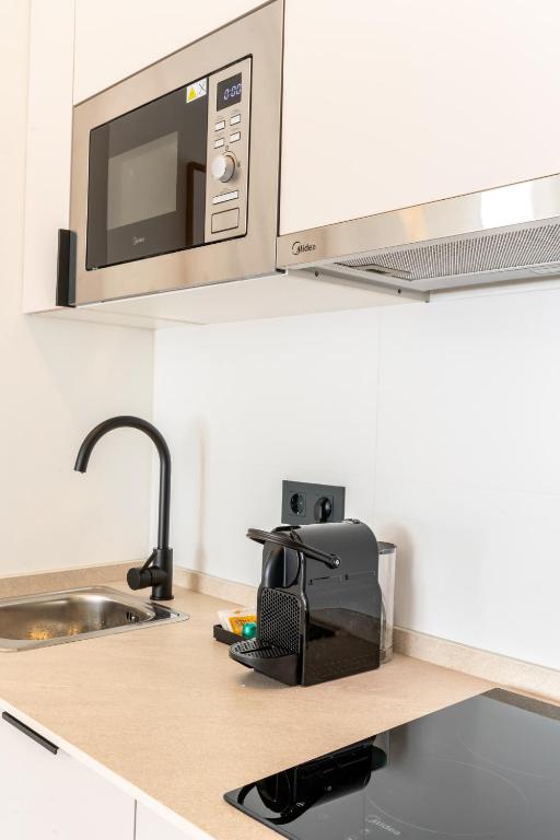 a kitchen counter with a sink and a microwave at Apartamentos Plaza España - Enjoy Sevilla in Seville