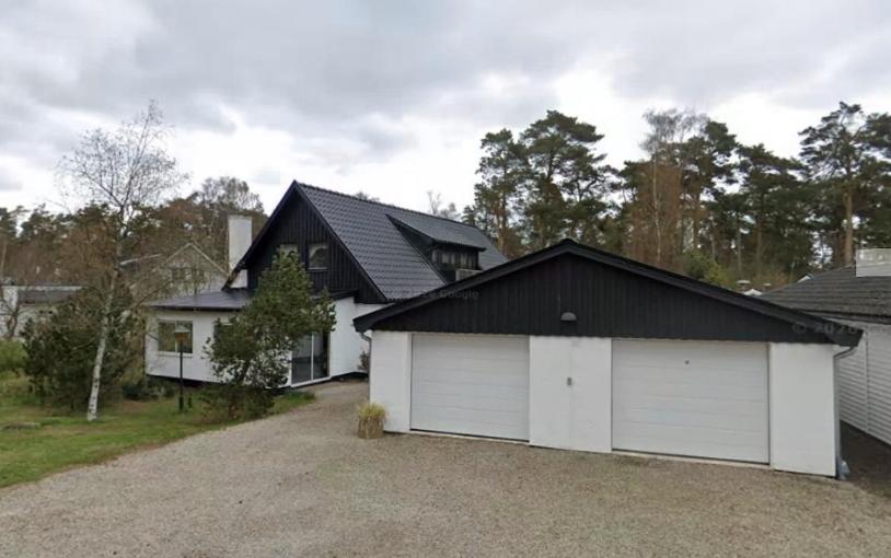 a house with a white garage and a black roof at Sandbybäcksvägen 1 in Borrby