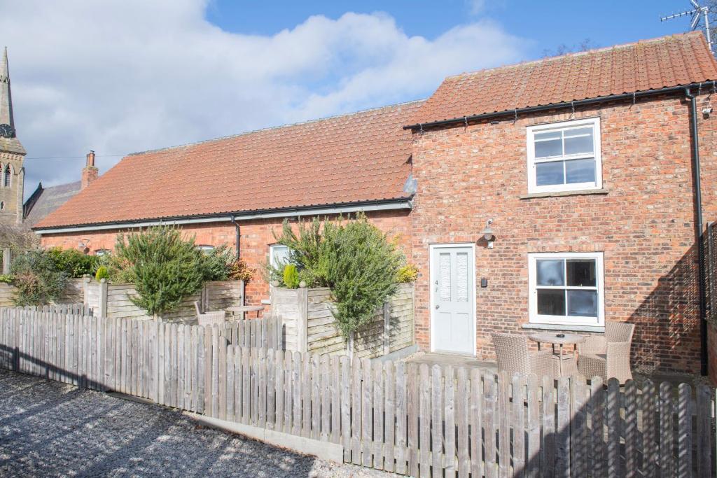 ein Backsteinhaus mit weißem Lattenzaun in der Unterkunft Carlton Towers Estate - Stapleton Rooms & Parkgate Cottages in Carlton