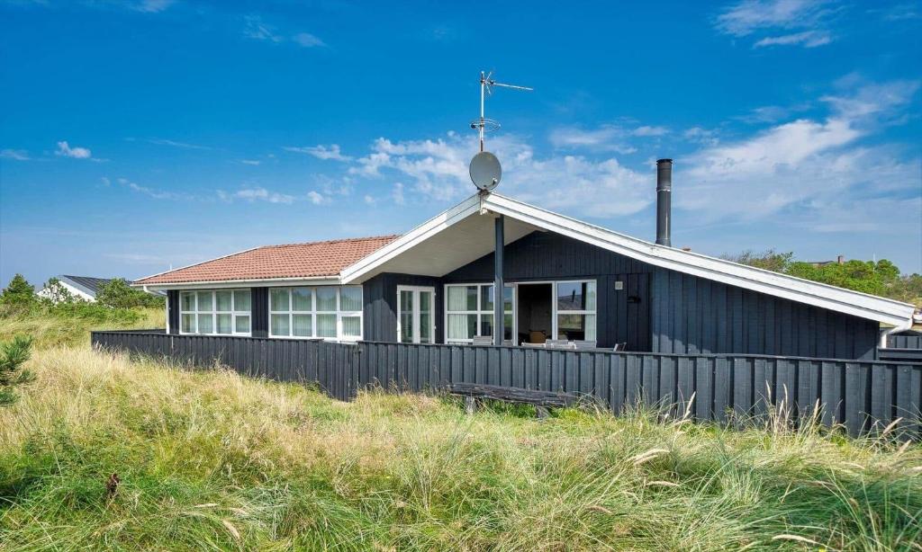 a black house sitting on top of a hill at VE265-Vejers-Strand-Nordvej-98-A in Vejers Strand