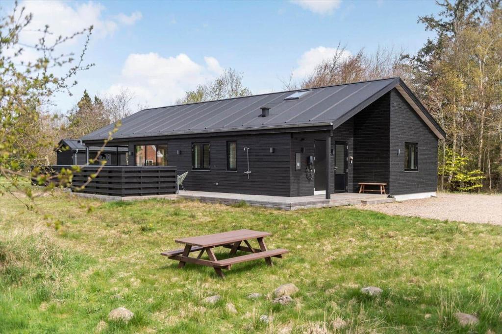 a black cabin with a picnic table in the grass at HS018-Henne-Hennebysvej-8 in Henne Strand